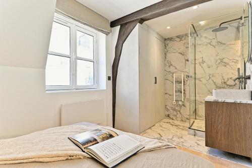 une chambre avec une douche et un livre sur un lit dans l'établissement Élégant esprit suite d'hôtel, à Paris