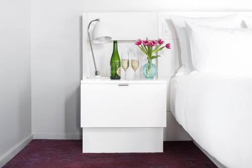 a white bedside table with wine glasses and flowers at 21c Museum Hotel Lexington in Lexington