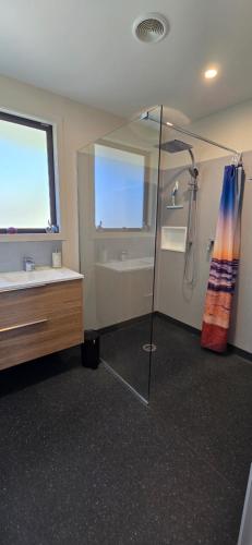 a bathroom with a shower and a sink and a tub at The Rocks Chalets in Takaka