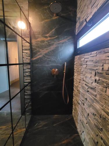 a shower in a room with a stone wall at A Frame Villas in Vrahati