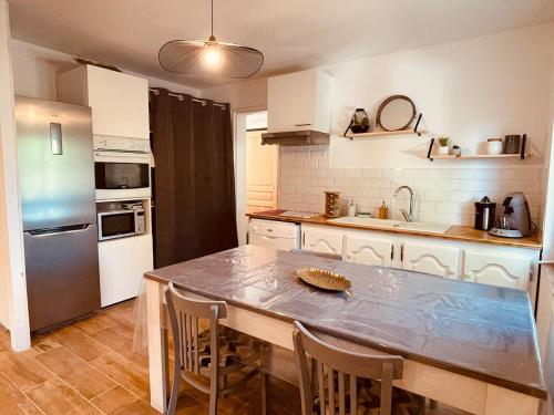 a kitchen with a table with chairs and a refrigerator at La maison Alba in Ganges