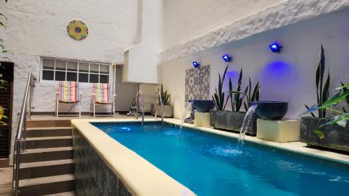 a swimming pool in a room with chairs and plants at Casa del Hidalgo Hotel Cali Centenario in Cali