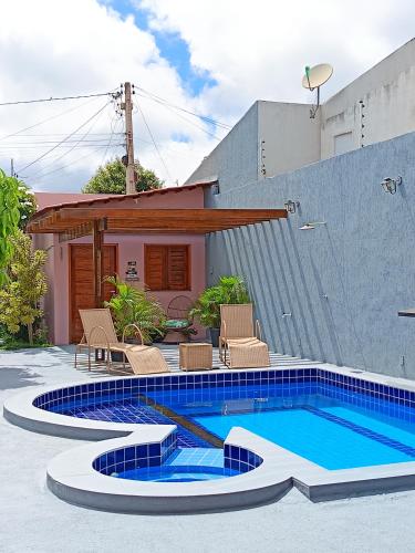 a swimming pool with chairs and a house at Quarto Sol Poente in Tianguá