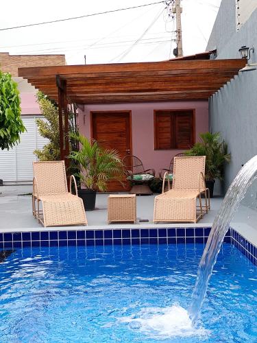 a swimming pool with two chairs and a fountain at Quarto Sol Poente in Tianguá