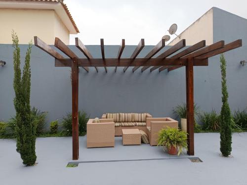 a pergola with a couch and chairs under it at Quarto Sol Poente in Tianguá