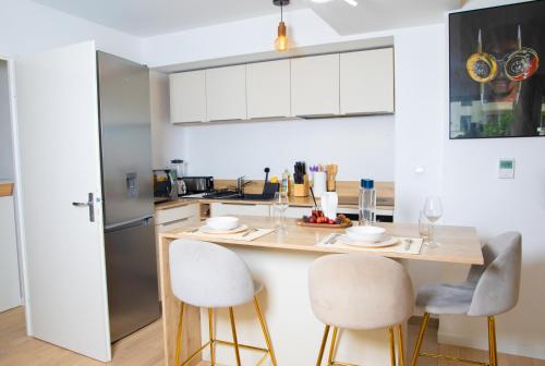 une cuisine avec un comptoir avec deux tabourets et une table dans l'établissement Le Tout élégant, à Colombes