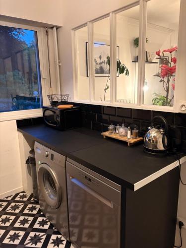 une cuisine avec un lave-linge et un comptoir noir dans l'établissement Appartement Rouen centre proche CHU, à Rouen