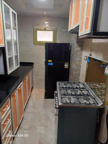 a kitchen with a stove and a black refrigerator at الفيروز شقه فندقيه الفيوم دله in Fayoum Center