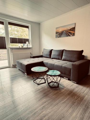 a living room with a couch and two tables at Apartment 4 - Haus Heinke am Deich in Friedrichskoog