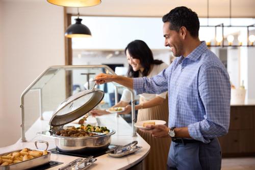 a man and woman preparing food in a kitchen at Staybridge Suites Great Falls by IHG in Great Falls