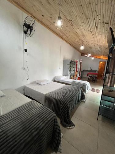 a room with two beds and a fan on the wall at Hospedaria Paraíso das Águas Suíte independente com cozinha completa in Itabirito
