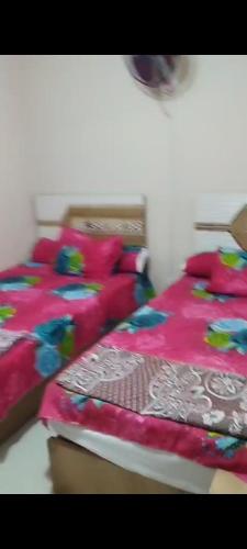 a bedroom with two beds with colorful blankets at وحدة للإيجار في إحدى قرى الساحل الشمالي المميزة in Dawwār Abū Maḩrūs