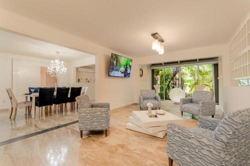 a living room with chairs and a dining room at Tropical 3 BDR Villa with pool By Casa Paraíso in Cancún
