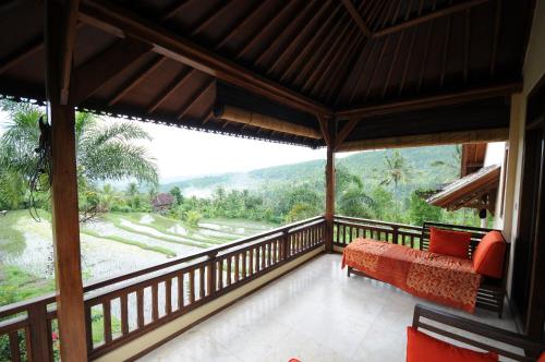 a room with a balcony with a couch and a view at Lesong Hotel and Restaurant in Munduk