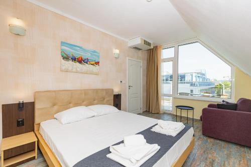 a bedroom with a bed and a couch and a window at Favorit Aparthotel in Sunny Beach