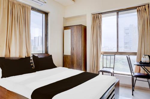 a bedroom with a bed and a chair and windows at Hotel O Destination 41 in Pune