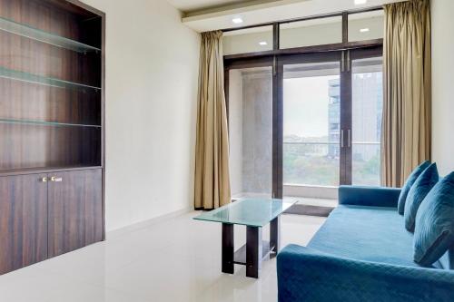 a living room with a blue couch and a glass table at Hotel O Destination 41 in Pune
