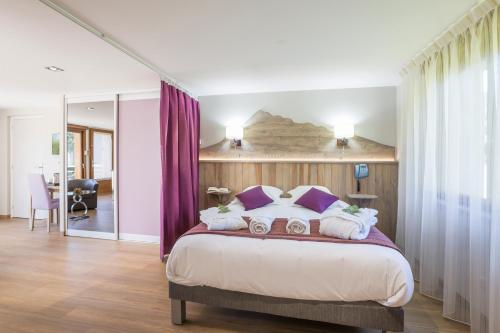 1 dormitorio con 1 cama grande y cortinas moradas en Logis Hôtel Le Relais du Bois Vialotte, en Le Chambon-sur-Lignon