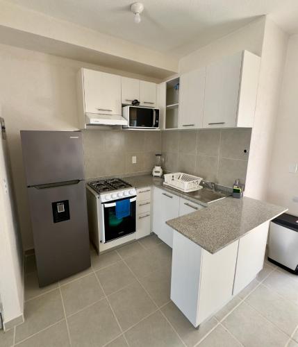 a kitchen with white cabinets and a stove top oven at Linda casa frente a alberca en Playa del Carmen in Playa del Carmen