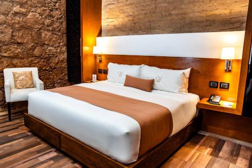 a bedroom with a large bed and a chair at Hotel Boutique Casa Madero in Morelia