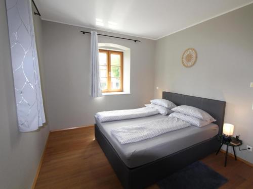 a bedroom with a bed with white sheets and a window at Residenz Aichwaldsee in Unteraichwald