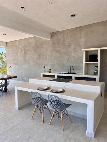 a kitchen with a large white counter and chairs at Casa Amarliz in La Majahua