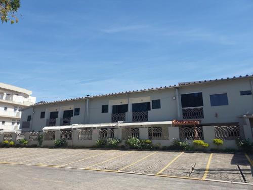 a white building with a fence in a parking lot at Apartamento Ubatuba 150m do mar Maranduba in Ubatuba