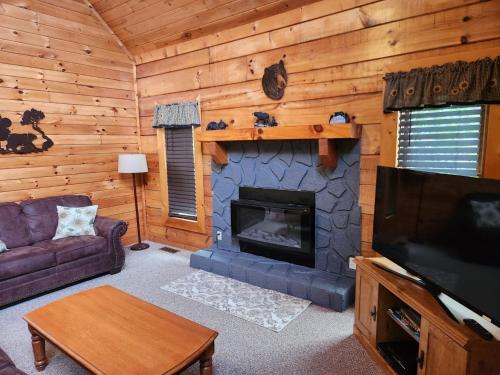 a living room with a fireplace and a tv at Story Brook: Beautiful true log cabin! Close to Dollywood, State Park, and more! in Sevierville