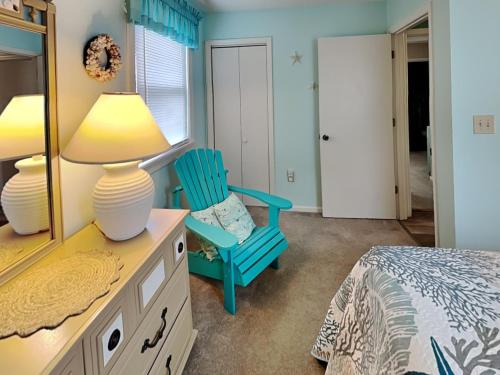 a bedroom with a blue chair and a mirror at Back A Bit in Surf City
