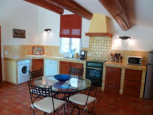 une cuisine avec une table en verre et des chaises dans l'établissement Luberon & Lavandes, à Roussillon