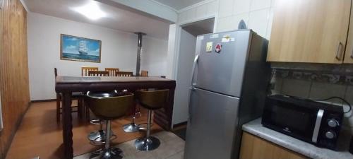 een keuken met koelkast en een bar met magnetron bij Alquiler House in Puerto Montt