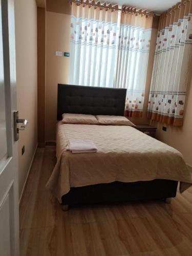 a bedroom with a bed and a window with curtains at Departamento en Huanchaco in Huanchaco