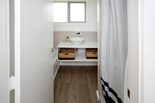 a white bathroom with a sink and a window at House Horse & Hound on Argelins in Hanmer Springs