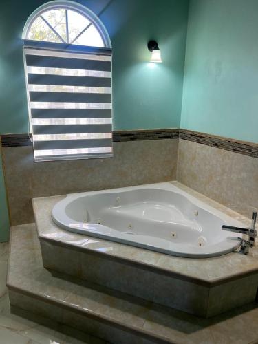 a large bath tub in a bathroom with a window at Whitehall Villa in Negril in Negril