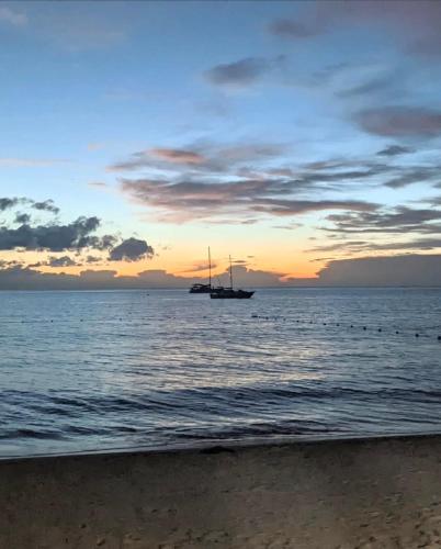 a boat in the ocean at sunset with a beach at Whitehall Villa in Negril in Negril