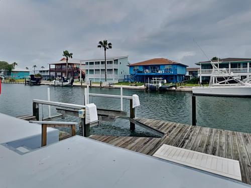 a dock with a bench and a boat on the water at Dolphin Paradise in Aransas Pass