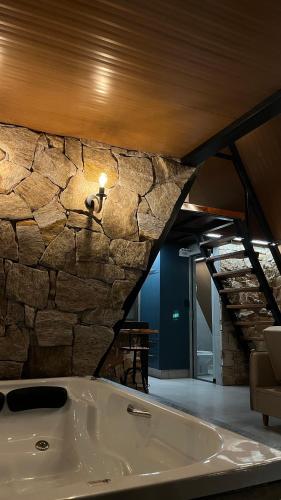 a bath tub in a room with a stone wall at Chalés Piribless-Oásis in Pirenópolis
