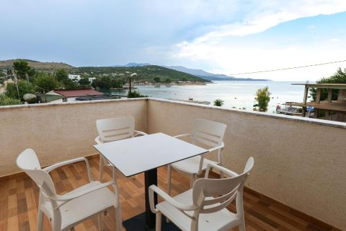 a table and chairs on a balcony with a view of the ocean at Sunset Bay Deluxe Villa in Ksamil