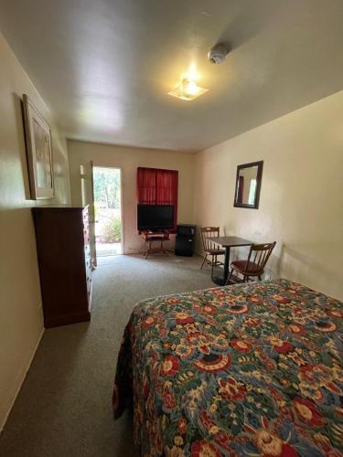 a hotel room with a bed and a table and chairs at Sierra Pelona Motel in Santa Clarita