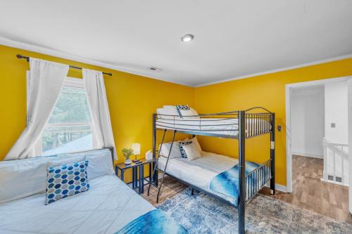 a bedroom with two bunk beds and yellow walls at Arcade, Ping Pong, Hot Tub, Gas Grill, & King Bed in Kernersville