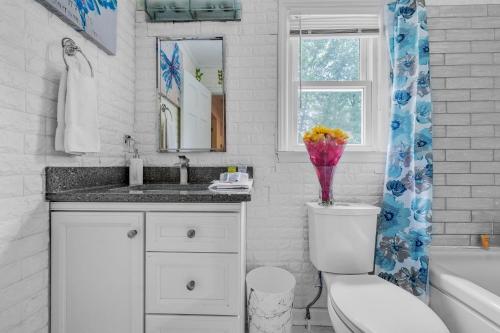 a bathroom with a toilet and a sink and a vase of flowers at Arcade, Ping Pong, Hot Tub, Gas Grill, & King Bed in Kernersville