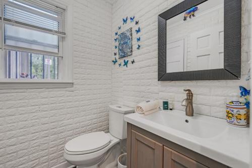 a white bathroom with a toilet and a sink at Arcade, Ping Pong, Hot Tub, Gas Grill, & King Bed in Kernersville