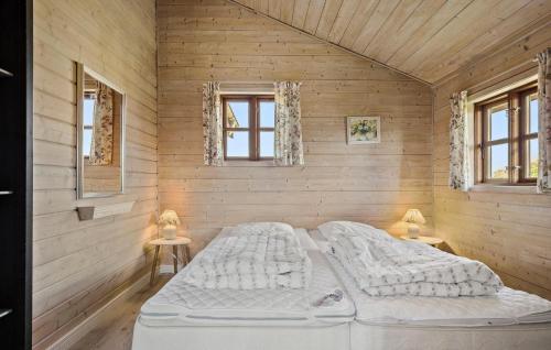 a bed in a wooden room with two windows at Awesome Home In Hvide Sande With Sauna in Havrvig