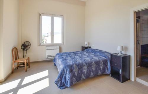 a bedroom with a bed with a blue comforter and a window at 5 Bedroom Nice Home In Bovalino in Bovalino Marina