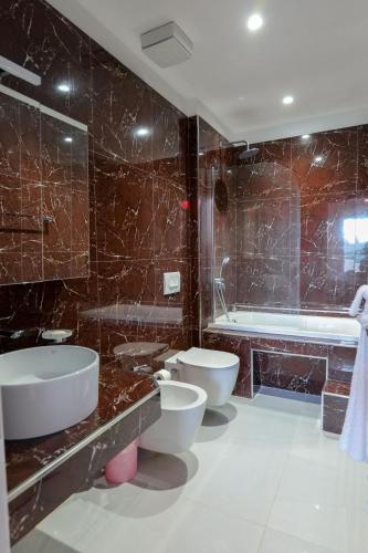 a bathroom with two sinks and a tub and two toilets at Sunset Bay Deluxe Villa in Ksamil