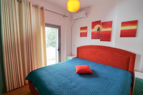 a bedroom with a blue bed with a red pillow at Sunset Bay Deluxe Villa in Ksamil