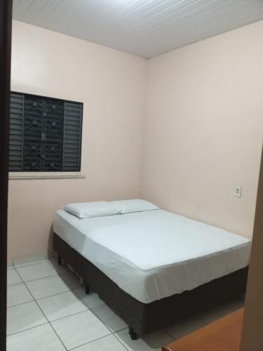 a bed in a white room with a window at Casa in Fortaleza