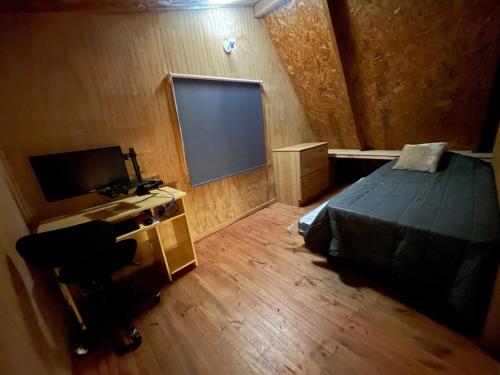 ein Schlafzimmer mit einem Bett, einem Bildschirm und einem Schreibtisch in der Unterkunft Cabaña Esperanza in Ancud