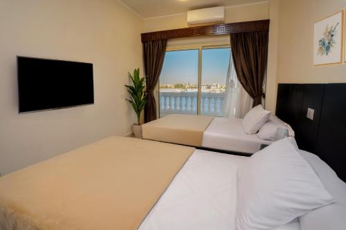 a hotel room with two beds and a flat screen tv at Nile Crown Luxor in Luxor