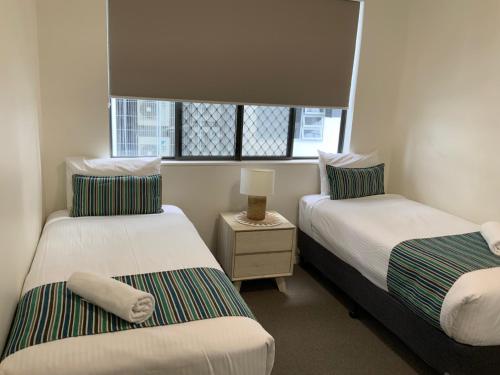 two beds in a small room with a window at Meridian Alex Beach Apartments in Alexandra Headland